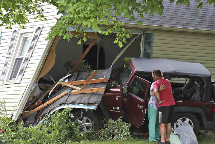 The driver of a Jeep is comforted by a friend after she lost control on South Bird Road and struck a house. The driver was not injured but a man, sleeping in the front bedroom of the house, was transported to the hospital with non-life threatening injuries.   (Bill Lackey / Springfield News-Sun)